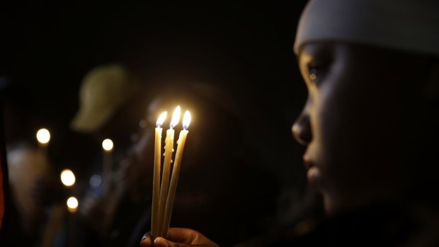 Chaunte Williams, 13, holds up three candles as she takes part in a vigil on Thursday in Ferguson.