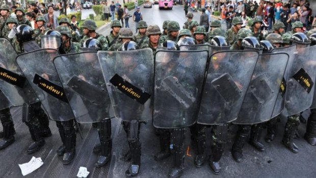 Thai army soldiers stand guard as anti-coup protesters rally nearby in Bangkok.