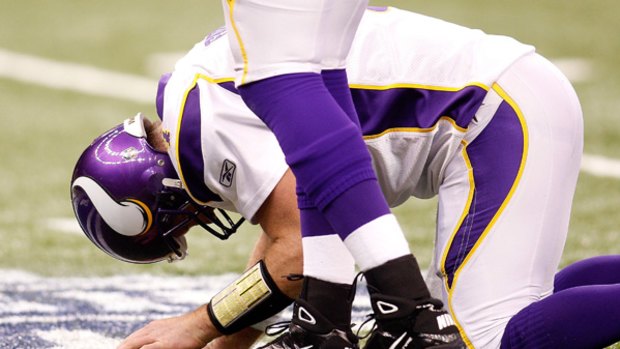 Quarterback Brett Favre of the Minnesota Vikings kneels on the turf in pain after taking a hard hit against the New Orleans Saints.