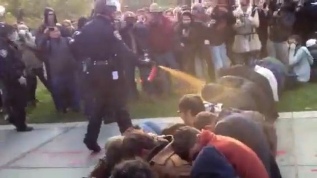 Easy target: An image from the widely circulated video showing a policeman spraying a line of sitting protesters at the Seattle demonstration last Tuesday.