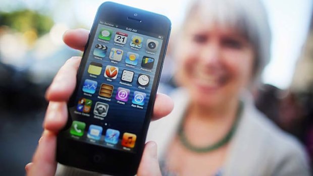 A customer shows off her new iPhone 5 outside Apple's Fifth Avenue flagship store.