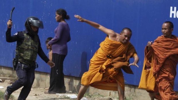A security guard chases away Buddhist monks from a camp occupied by anti-government demonstrators in Phnom Penh. 