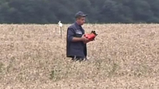 A rescue worker carries what is believed to be a flight data recorder at the crash site.