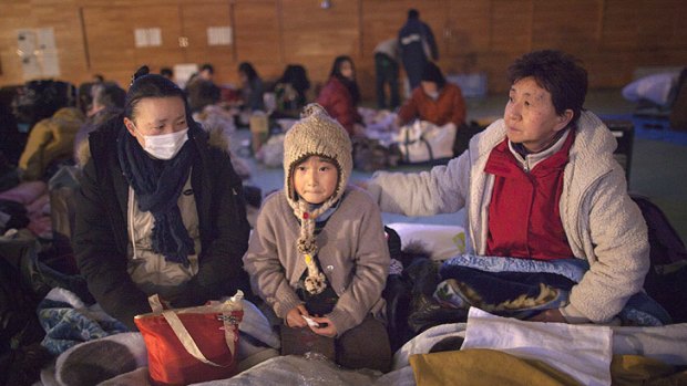 Yukie Ito, left, tries to comfort her daughter Hana, 8, at a cold refugee centre for the homeless in Kesennuma, Miyagi prefecture.