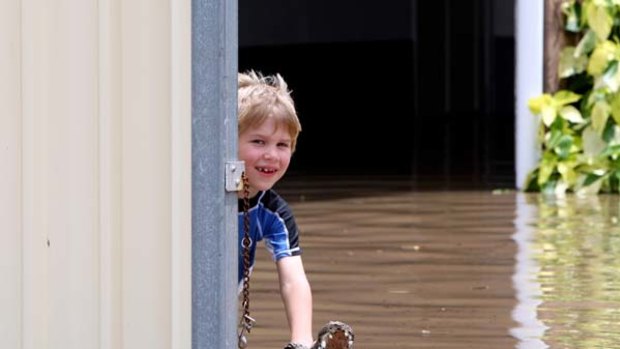 Life in the Big Wet ... Rockhampton resident Matthew Steffen plays a joke on passers-by with a plastic crocodile.