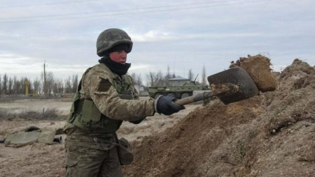 A Ukrainian serviceman digs a trench at a checkpoint near the village of Strelkovo in Kherson region adjacent to Crimea.