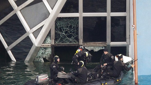 Marina Militare scuba divers prepare to enter a broken window of the Costa Concordia.