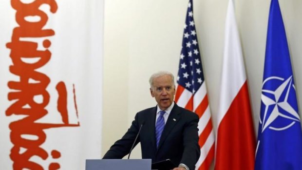 US Vice-President Joe Biden addresses the media in Poland, with US, Polish and NATO flags behind him, as well as a banner from the Solidarity movement which weakened Soviet control over Poland in the 1980s. 