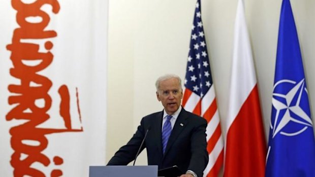 US Vice-President Joe Biden addresses the media in Poland, with US, Polish and NATO flags behind him, as well as a banner from the Solidarity movement which weakened Soviet control over Poland in the 1980s. 