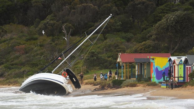 A yacht is washed ashore as large waves hit the Mornington pier during a storm. 