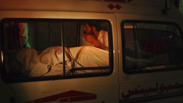 A man sits beside the body of a woman who was killed on board a Pakistan International Airlines plane, as the ambulance carrying them arrives at a hospital in Peshawar.