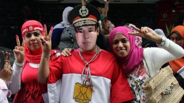 Egyptian supporters of ex-army chief Abdel Fattah al-Sisi, one with a mask bearing his portrait, flash the sign of victory in a street on the first day of the two-day election for a new president.