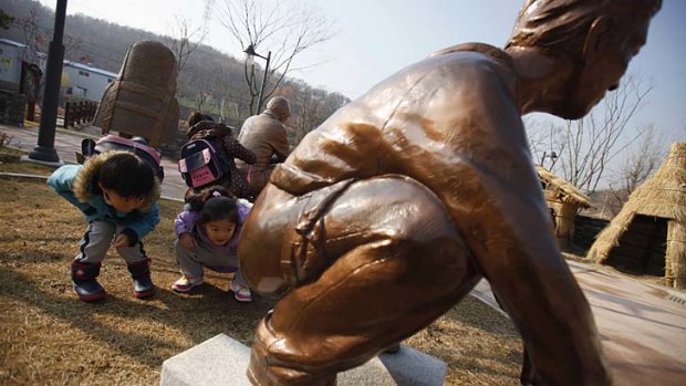 Kindergarden children look at a statue of a man responding to the call of nature at the Toilet Culture Park in Suwon.