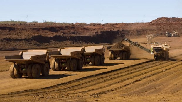 Haul trucks wait to be loaded with iron ore at a Fortescue Metals Group mine in West Australia's Pilbara region.
