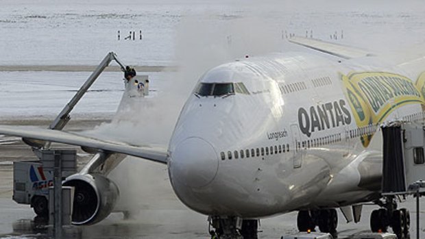 Workers de-ice a Qantas jet at Heathrow.