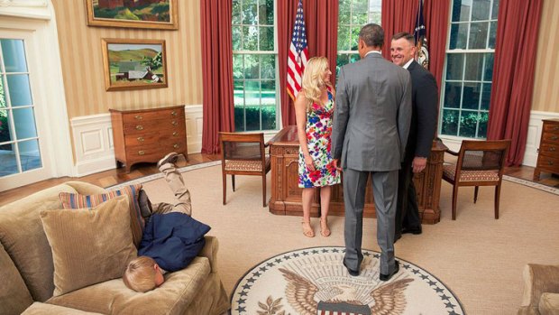 Must be a Republican ... President Barack Obama visits with a departing United States Secret Service agent and his wife as their son dives into a couch in the Oval Office.