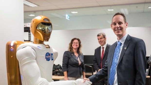 Woodside Energy chief technology officer Shaun Gregory shakes the Robonaut's hand at Woodside's Perth office.
