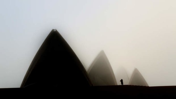 A tourist takes a photo of the Opera House as fog blankets Sydney.