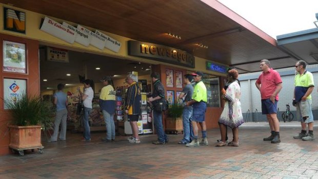 People line up at the Dickson news agency  to buy tickets for tonight's Oz Lotto, which has jackpotted to $100 million.