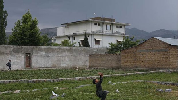 Resident boy Adeel, 8, plays with a tennis ball in front of the compound.