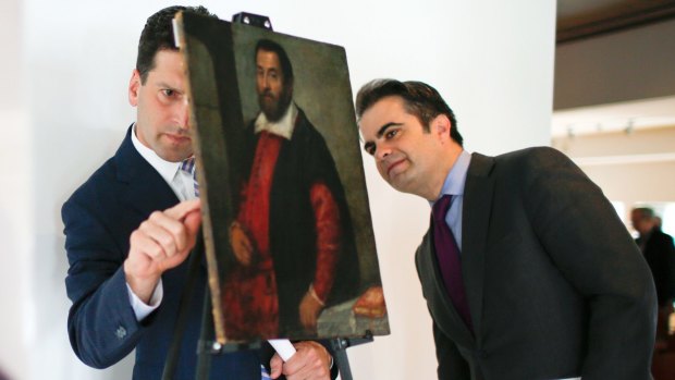 Benjamin Lawsky (left) of the New York State Department of Financial Services examines the back of the painting <i>Portrait of a Man</i>.