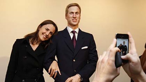 A guest poses for a photograph with a wax figure of Britain's Prince William during a party launching the exhibition at the Stephen Friedman Gallery in London.