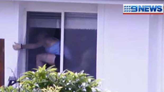 Police help a woman out of a Banyo house during a siege on Boxing Day.