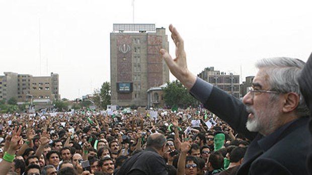 Iran's defeated presidential candidate Mir Hossein Mousavi waves to the crowd during a massive rally in Tehran's Imam Khomeini square yesterday.