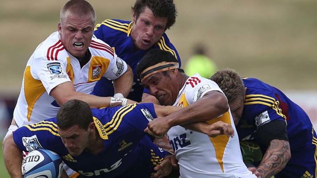 Gareth Anscombe and Tanerau Latimer of the Chiefs tackle Shaun Treeby of the Highlanders.