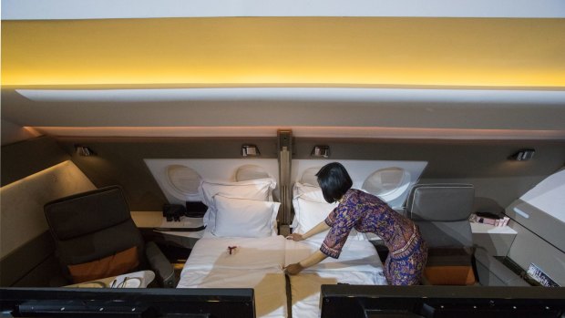 A flight attendant arranges a bed in two adjoining suites on a Singapore Airlines Airbus A380.