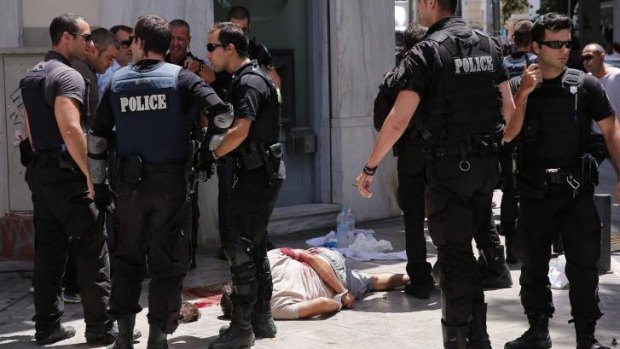 Nikos Maziotis lays wounded on a sidewalk, surrounded by police after a shootout at the tourist area of Monastiraki in central Athens on Wednesday. 