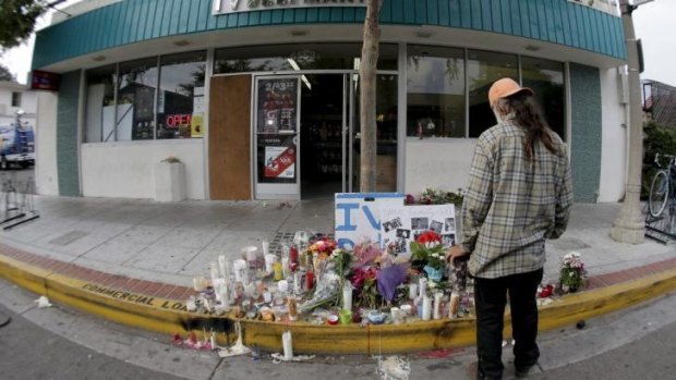 A passerby pays his respects at a makeshift memorial in front of the IV Deli Mart, where police say Elliot Rodger shot and killed Christopher Michaels-Martinez on Friday night.