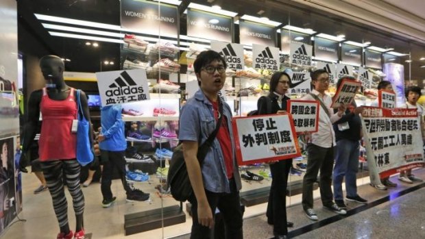 Protesters hold banners and placards during a protest outside an Adidas shop at a shopping mall during Labour Day in Hong Kong.