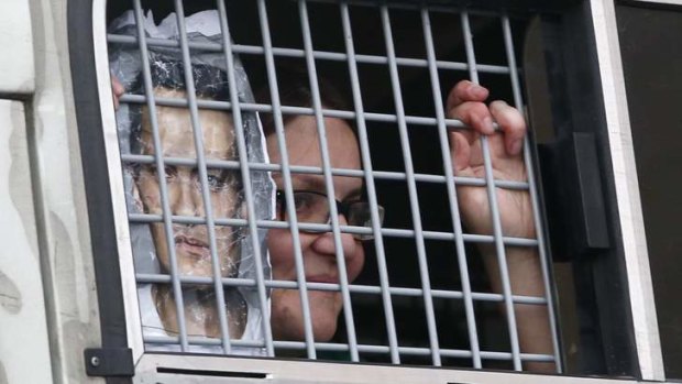 A woman holding a portrait of Russian opposition leader Alexei Navalny looks out from a police bus after being detained during a protest against the verdict of a court in Kirov, Russia.
