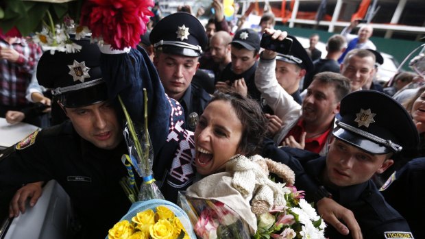 Ukraine's Jamala, centre, surrounded by policemen greets her supporters upon her arrival in Kiev.
