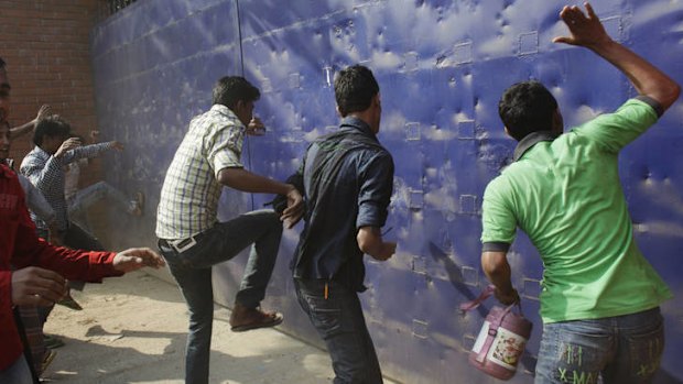 Anger ... workers try to break the gate of a garment factory during a protest against the conditions that have caused regular fire tragedies.