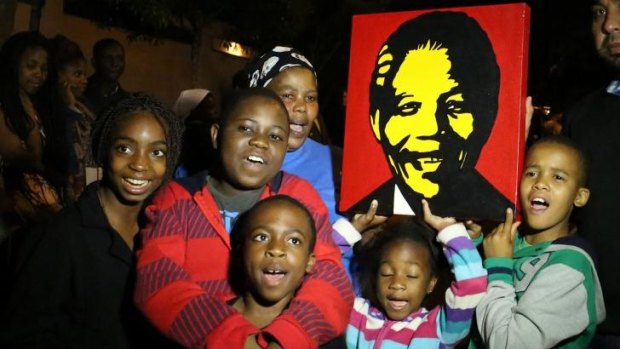 South Africans hold pictures of former South African president Nelson Mandela as they pay tribute following his death.
