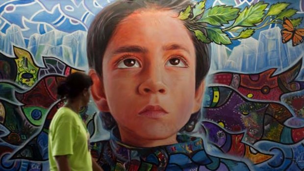 A woman walks past a mural in the climate village during the United Nations Framework Convention on Climate Change, in the Mexican seaside resort of Cancun.