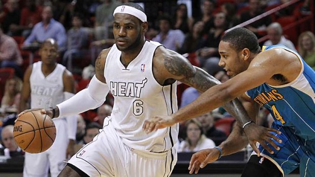 Miami Heat's LeBron James dribbles past New Orleans Hornets'  Xavier Henry.