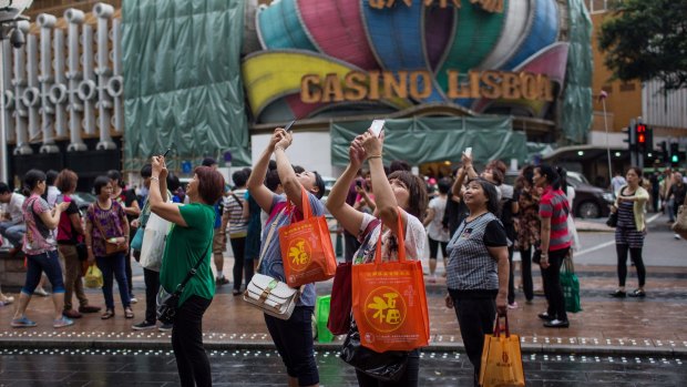 People take photographs with mobile phones outside the Casino Grand Lisboa, in Macau. 