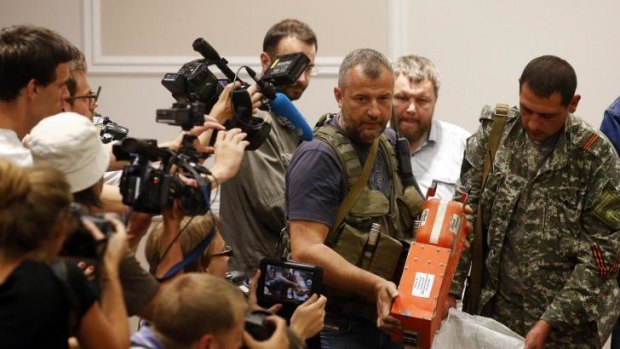 A pro-Russian separatist shows members of the media a black box belonging to Malaysia Airlines flight MH17, before its handover to Malaysian representatives, on Tuesday.