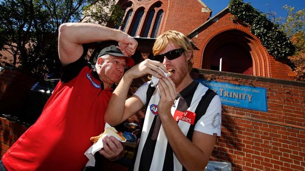 Graham Jenkin and Lachie Mika partake in a sausage sizzle outside the Holy Trinity Anglican Church in East Melbourne on Anzac Day.