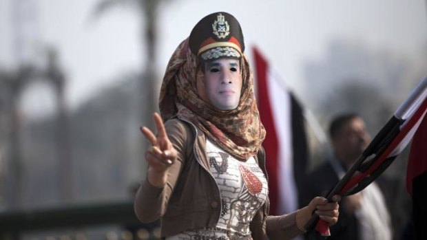 A woman wears a mask depicting Defence Minister Field Marshal Abdel Fattah Al-Sisi.