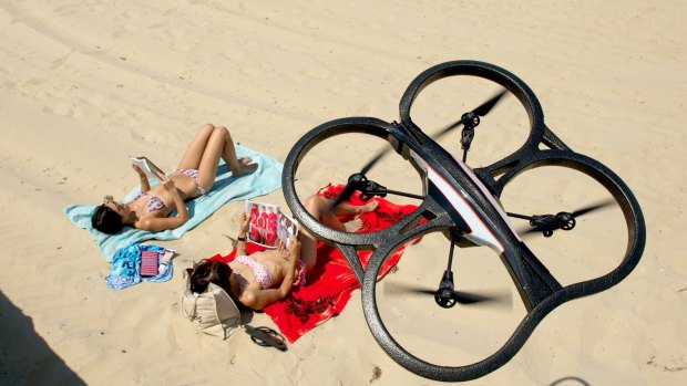 A remote controlled drone helicopter that can record video and photos hovers above sun bathers at Middle Park beach.