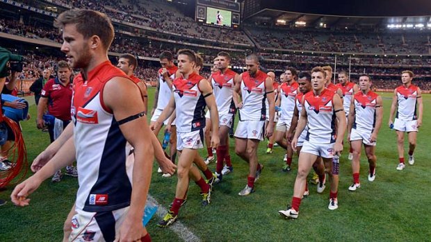 The Demons leave the field after their 148-point loss to Essendon.
