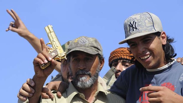 Libyan National Transitional Council fighters hold what they claim to be the gold-plated gun of the late Libyan leader.