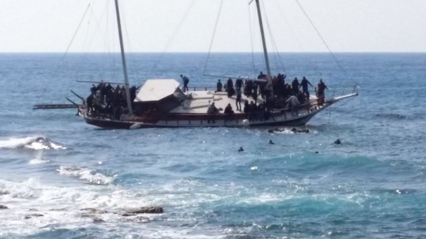 Migrants swim to reach the shore as others remain are on a listing vessel that later sunk in the eastern Aegean island of Rhodes, Greece.