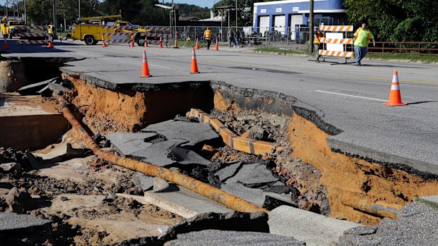 Workers block a road damaged by floodwaters caused by rain from Hurricane Matthew in North Carolina.