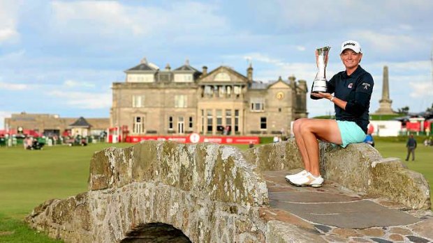 Lewis poses with the trophy on the Swilcan Bridge on the fairway of the 18th hole.