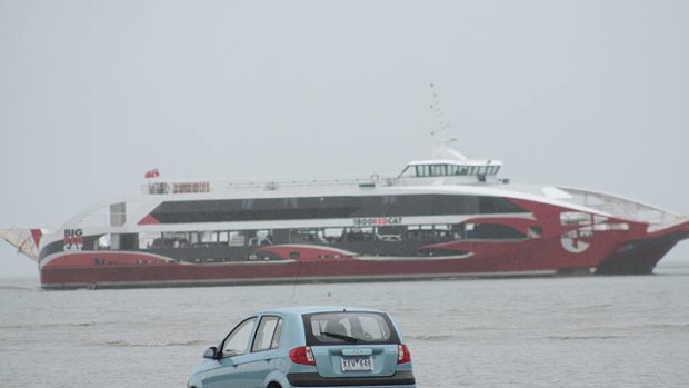 The Big Red Cat sails past the tourists' car. The low tide and a GPS navigation system lured them into the bay at Oyster Point at Cleveland.